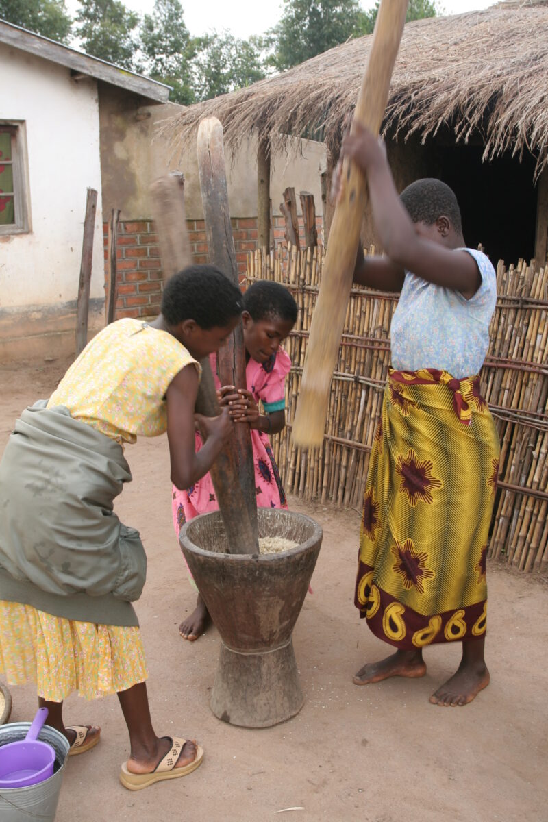 Pounding the Maize — Three Women pond maize into corn flour in Malawi — Malawi, Africa, food processing, pounding, women
