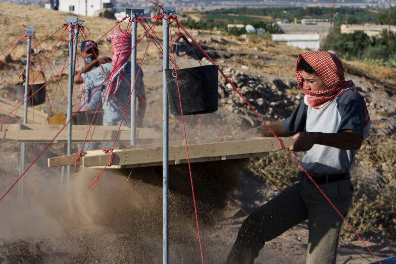 Sifting for Treasure — Students and Local workers, hired for the dig session, sift through the dirt that comes out of the squares, to catch small items like ...