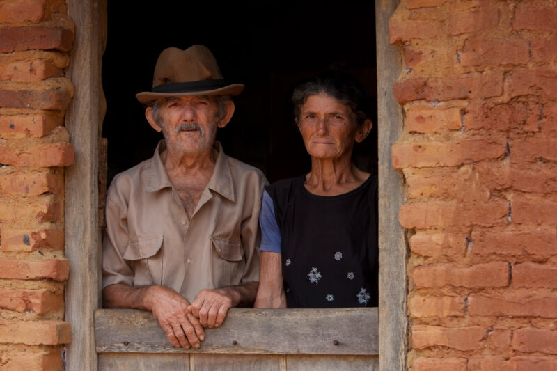 Living in Poverty — Elderly couple living in a desert region of Brazil look out the window of their home. — Brazil, South America, faces, poverty, poor