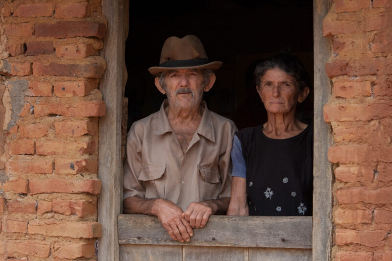 Living in Poverty — Elderly couple living in a desert region of Brazil look out the window of their home. — Brazil, South America, faces, poverty, poor