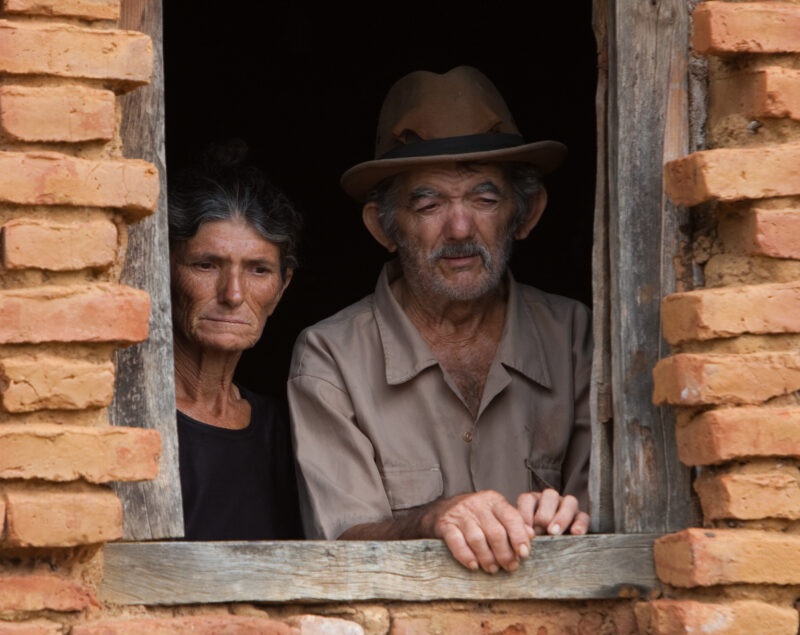 Living in Poverty — Elderly couple living in a desert region of Brazil look out the window of their home. — Brazil, South America, faces, poverty, poor