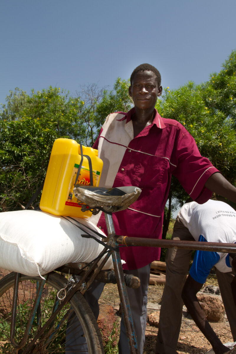 Food Distribution — Taking home food on the back of a bicycle. — Africa, West Africa, Burkina Faso, poor, poverty