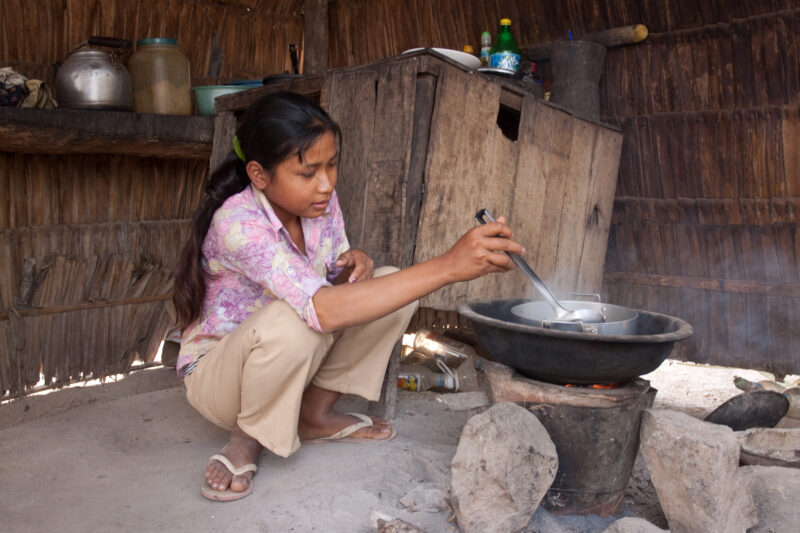 Cooking in Cambodia — Stock image of young girl in Cambodia cooking over an open fire. — Cambodia, ADRA, faces, children, girls