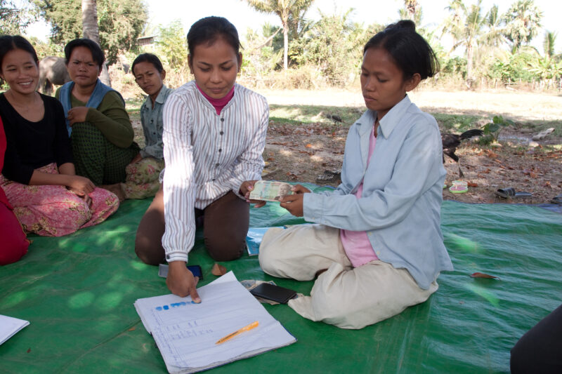 Micro Finance in Cambodia — Woman places her finger print on the account book to receive a small, low interest loan from the co-op of the woman's group that ...
