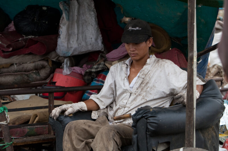 Taking a Rest — Young man takes a rest from his work at a dump in Cambodia where he searches for items that he can sell to recyclers. — Cambodia, man, men, r...