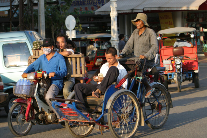 Street Scene in Phnom Penh — Stock Image of Cyclo driver with customer on the streets of Phnom Penh Cambodia — Cambodia, Phnom Penh, Cyclo, driver, motor sco...