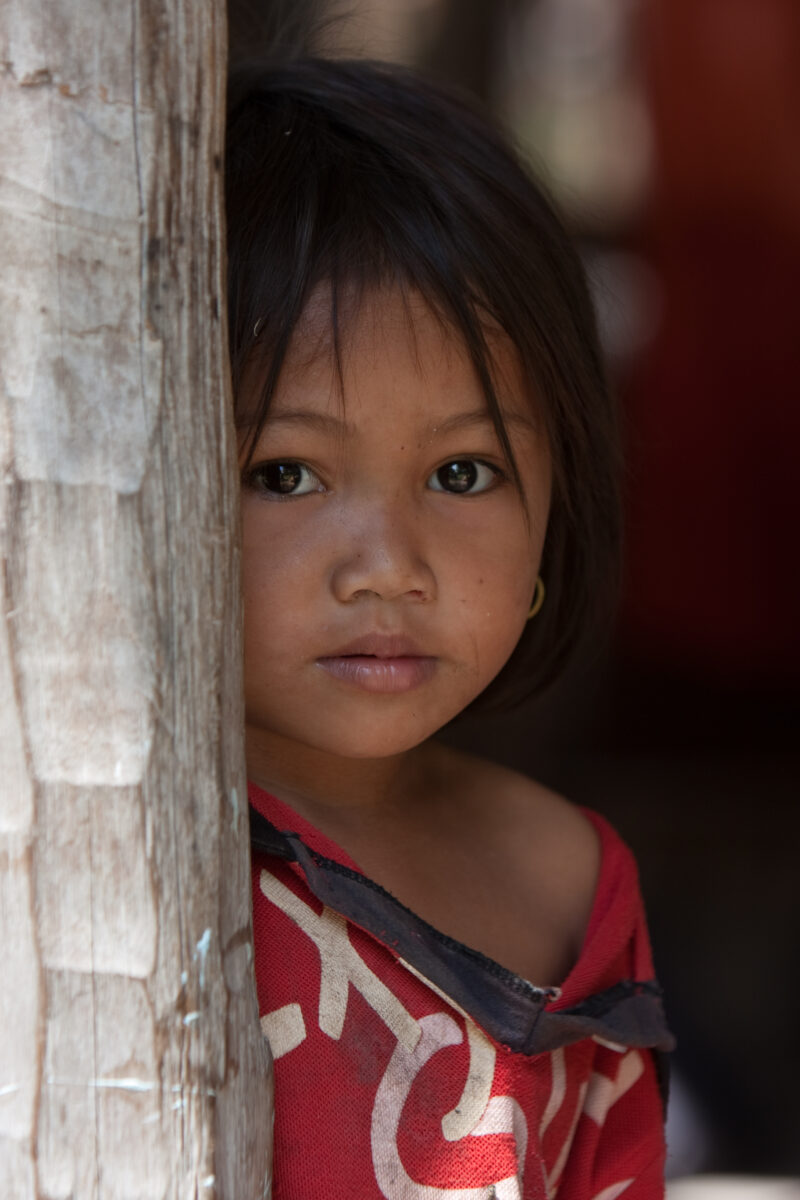 Girl by Post in Cambodia — Young girl peeks around a post at her home in Cambodia — Cambodia, faces, child, children, poor