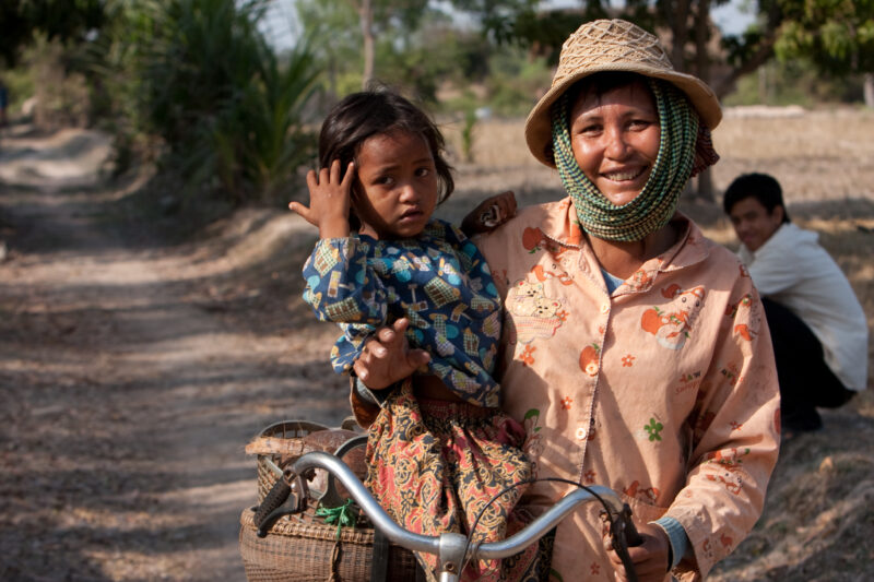 Mother and Daughter in Cambodia — Stock Image of a woman holding her daughter and her bicycle in rural Cambodia — Cambodia, woman, women, mother, gril