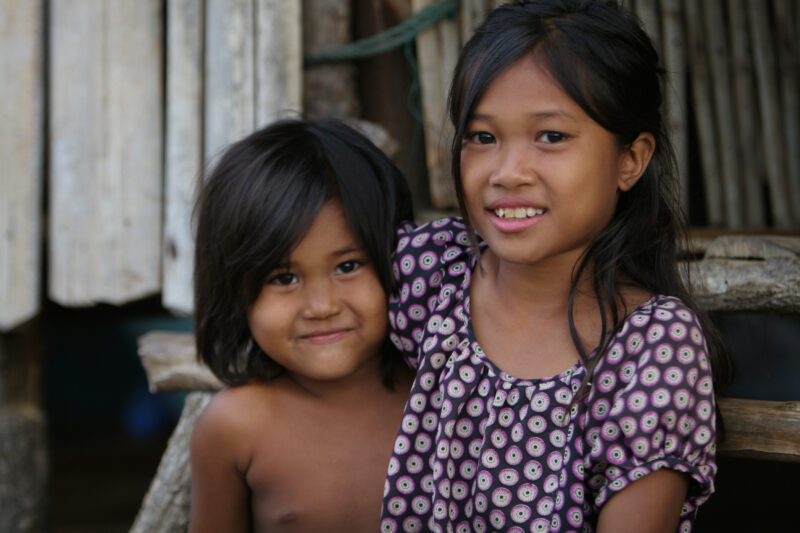 Sisters in Cambodia — Stock image of young girls in Cambodia sitting on the steps of their simple home in rural Cambodia — Cambodia, faces, children, girls, ...