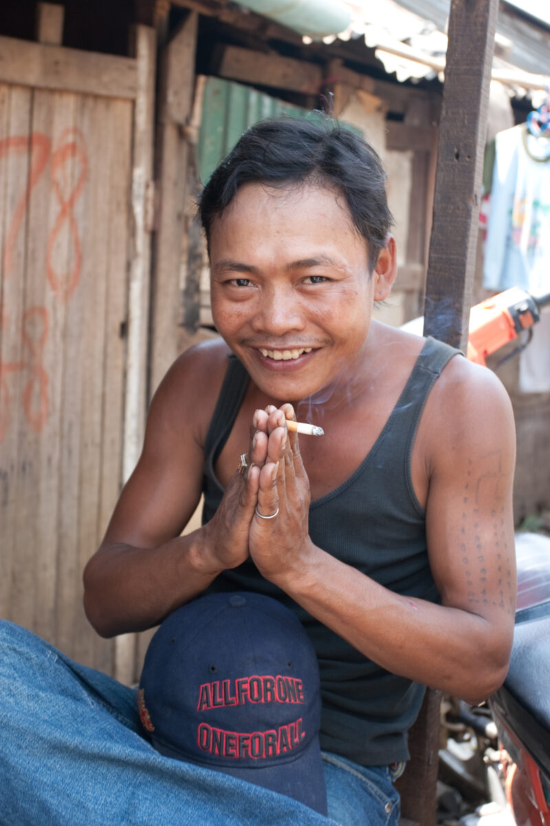 Smoking Man in Cambodia — Stock Image of Cambodia: Man gives a traditional greeting while holding a cigarette in his hand. — Cambodia