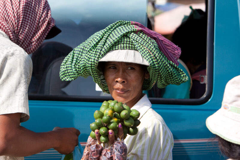 Street Vender in Cambodia — Stock Image of a woman selling limes on the street to people in cars as they stop at a light. — Cambodia, woman, vender, street v...
