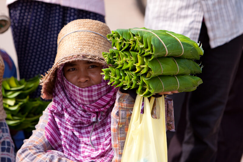 Street Vender in Cambodia — Woman tries to make a little money selling snacks wraped in leaves on a street in Phnom Penh, cambodia — Cambodia, street vender,...