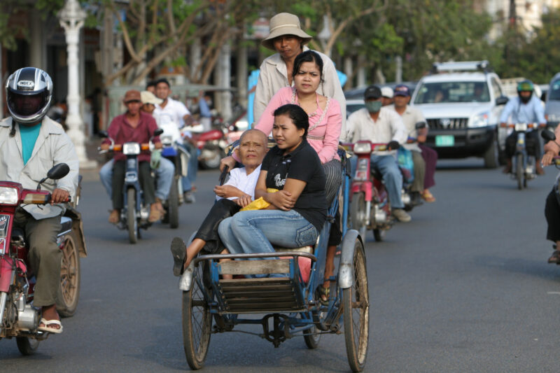 Cyclo Driver in Cambodia — Stock image of cyclo driver working the streets of Phnom Penh, Cambodia: with Three passengers stuffed into his cart. — Cambodia, ...