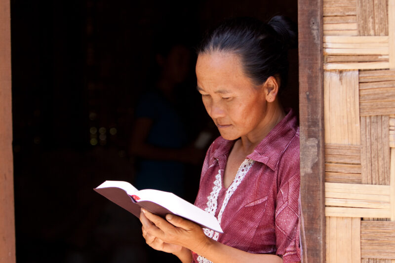 Bible Study in Laos — Woman reads the Bible in the doorway of her home in Laos — Laos, Southeast Asia, woman women, christian, ethnic