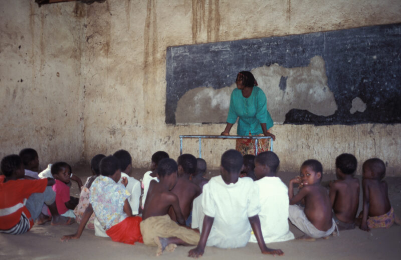 School in Malawi Africa — Teacher at a table with students on the floor at a school in rural Malawi — Malawi, school, poor, poverty, poor classroom