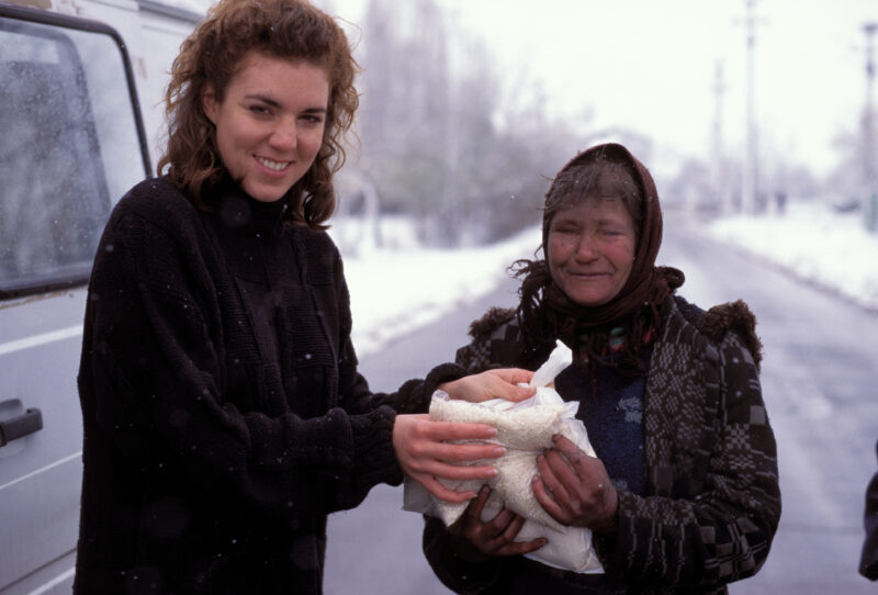 Food Assistance in Romania — A volunteer student from the US hands out food to a woman in need in Romania — Emergency, Disaster, food, security, distribution