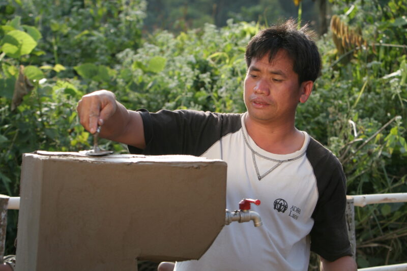 Installing the Water tap in Laos — ADRA worker installs a water tap, part of a larger gravity -fed water system in a ethnic minority village in Laos — Laos, ...