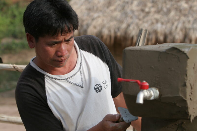 Installing the Water tap in Laos — ADRA worker installs a water tap, part of a larger gravity -fed water system in a ethnic minority village in Laos — Laos, ...