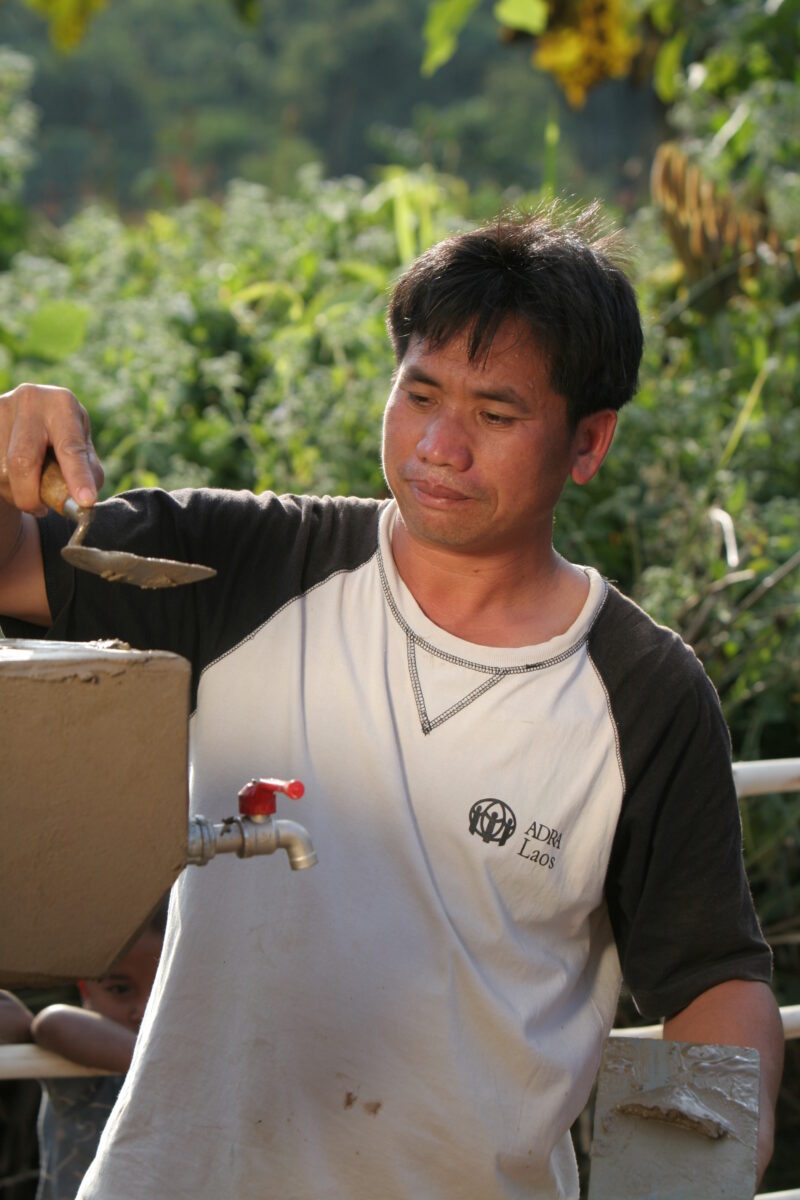 Installing the Water tap in Laos — ADRA worker installs a water tap, part of a larger gravity -fed water system in a ethnic minority village in Laos — Laos, ...