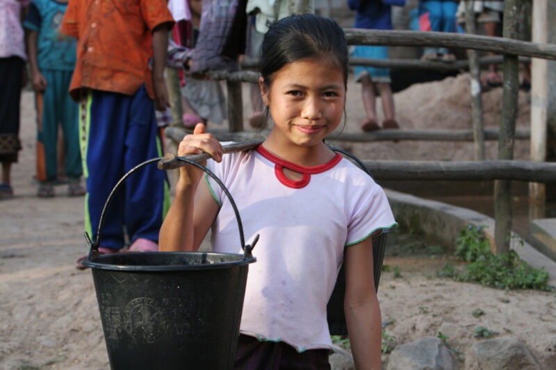 Girl at Water Tap in Laos — Stock Image of a girl at a water tap, part of a village wide gravity fed water system installed in a remote village in Laos with ...