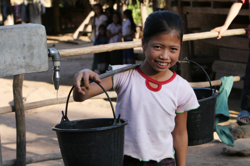 Girl at Water Tap in Laos — Stock Image of a girl at a water tap, part of a village wide gravity fed water system installed in a remote village in Laos with ...