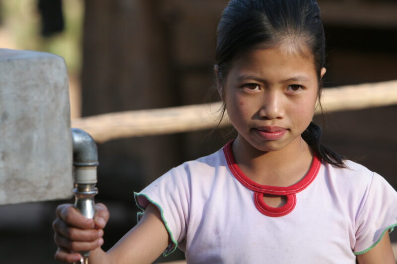 Girl at Water Tap in Laos — Stock Image of a girl at a water tap, part of a village wide gravity fed water system installed in a remote village in Laos with ...