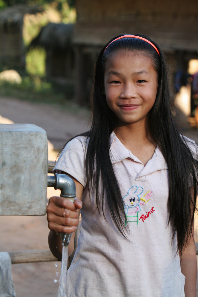 At the Water tap in Laos — Stock Image of a girl at a water tap, part of a village wide gravity fed water system installed in a remote village in Laos with t...