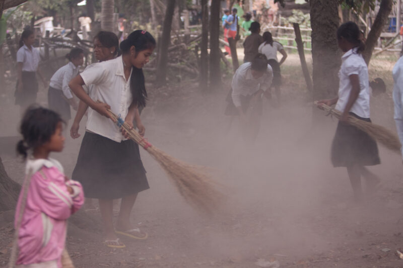 Cleaning Village in Cambodia — Children clean up the playground are of their school as part of a sanitation initiative to clean up their village, as challeng...