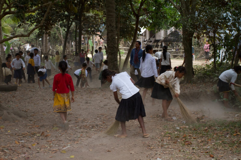Cleaning Village in Cambodia — Children clean up the playground are of their school as part of a sanitation initiative to clean up their village, as challeng...