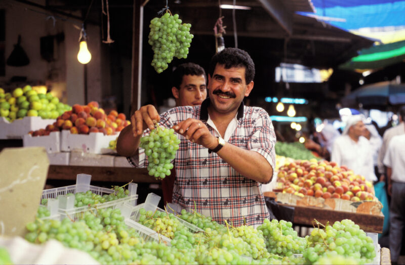 Man in Jordan market — Fruit vender in Jordan shows off his grapes. — Rural, men, man, faces, poor