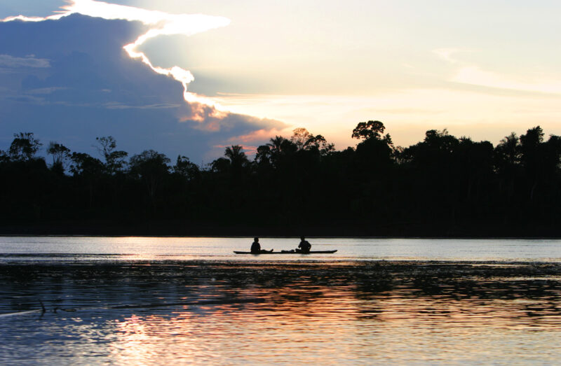 Ucayali River at Sunset — Two men in their dugout canoe are silhouetted in the sunset on the Ucayali River in Peru — Ethnic Minority, Shipibo Indians, Ucayal...