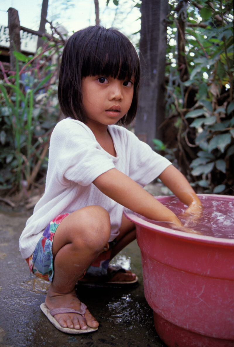 Washing Up in the Philippines — Young girl does dishe with water from the ADRA well in her village — Philippines, water, uses of water, dishes, girl