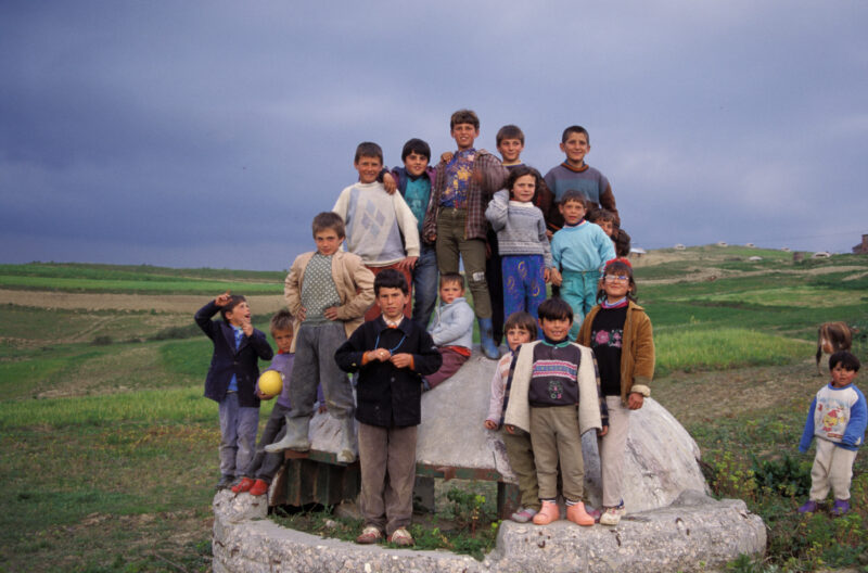 Children of Albania — A group of children pose around one of the thousands of concrete bunkers left over from the rule of Hoxha. — Albania, children, bunker,...
