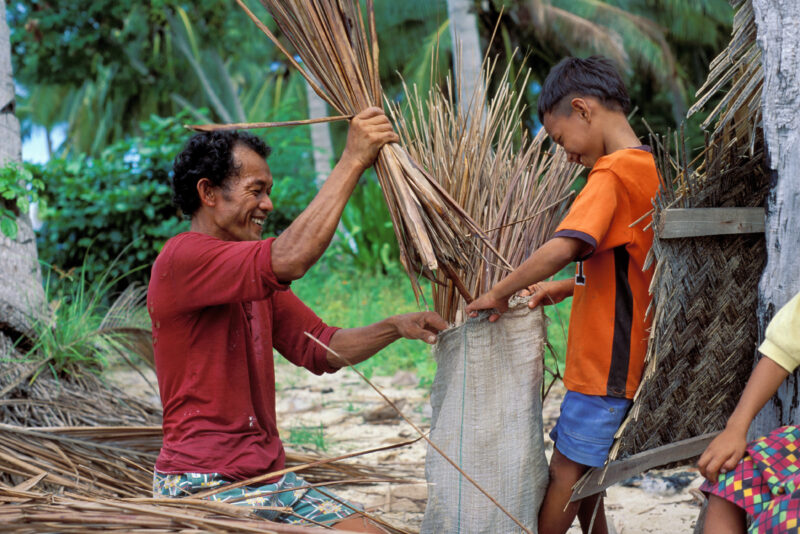 Boy helping his Father — Boy in a fishing village in the Phillipines helps his father — Philippines, Man, boy, father, reeds