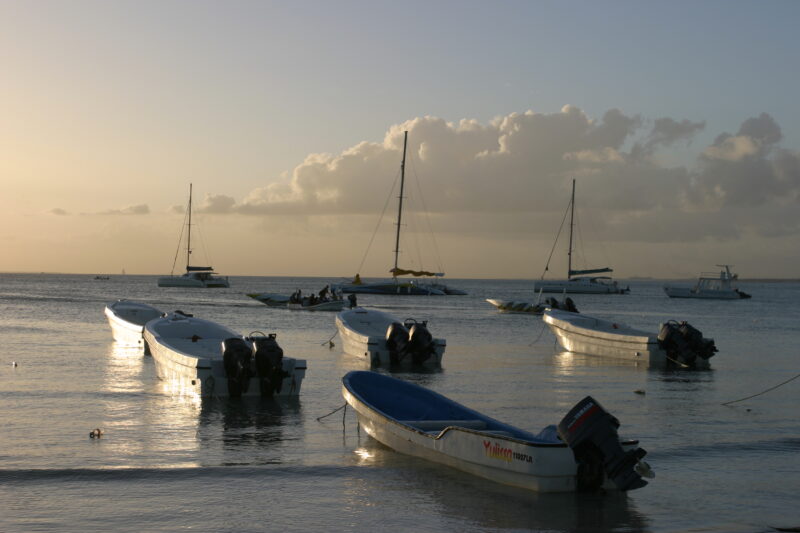 Sunset in the Dominican Republic — Boats and their drivers are silhouetted by the setting sun at a beach near La Romana, in the Dominican Republic — Dominica...