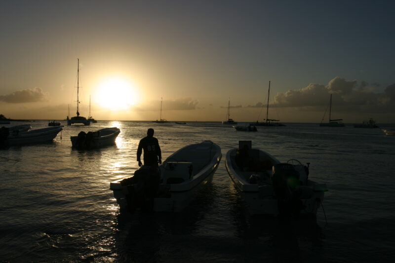 Sunset in the Dominican Republic — Boats and their drivers are silhouetted by the setting sun at a beach near La Romana, in the Dominican Republic — Dominica...
