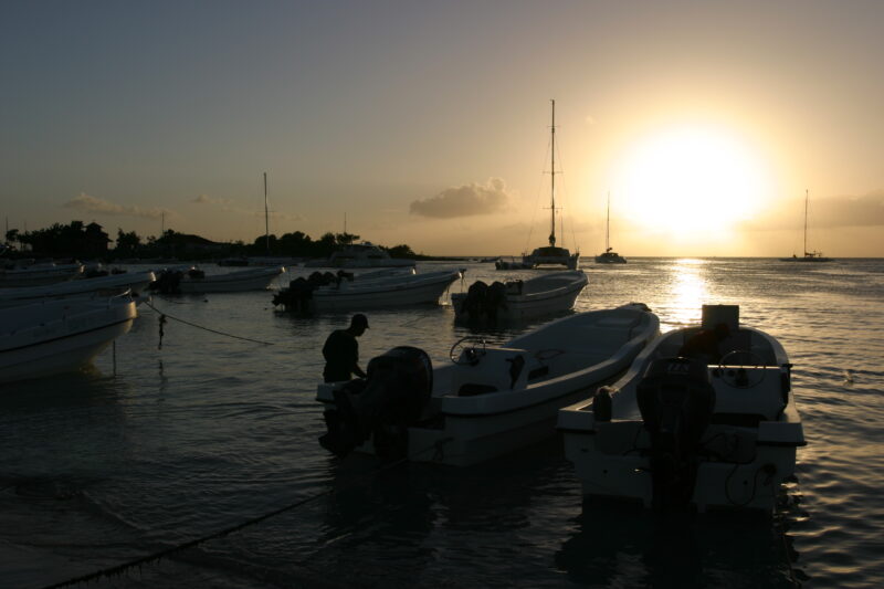 Sunset in the Dominican Republic — Boats and their drivers are silhouetted by the setting sun at a beach near La Romana, in the Dominican Republic — Dominica...