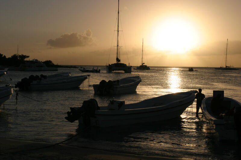 Sunset in the Dominican Republic — Boats and their drivers are silhouetted by the setting sun at a beach near La Romana, in the Dominican Republic — Dominica...