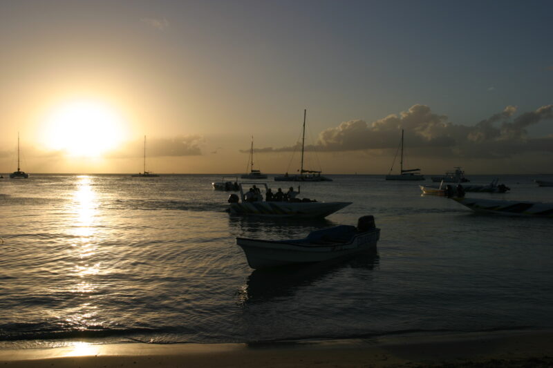 Sunset in the Dominican Republic — Boats and their drivers are silhouetted by the setting sun at a beach near La Romana, in the Dominican Republic — Dominica...
