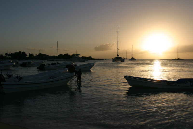 Sunset in the Dominican Republic — Boats and their drivers are silhouetted by the setting sun at a beach near La Romana, in the Dominican Republic — Dominica...