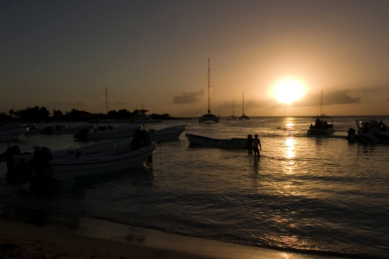 Sunset in the Dominican Republic — Boats and their drivers are silhouetted by the setting sun at a beach near La Romana, in the Dominican Republic — Dominica...