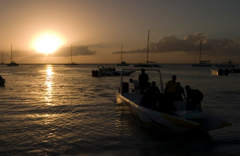 Sunset in the Dominican Republic — Boats and their drivers are silhouetted by the setting sun at a beach near La Romana, in the Dominican Republic — Dominica...