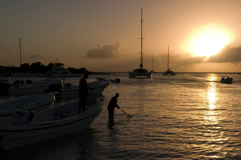 Sunset in the Dominican Republic — Boats and their drivers are silhouetted by the setting sun at a beach near La Romana, in the Dominican Republic — Dominica...