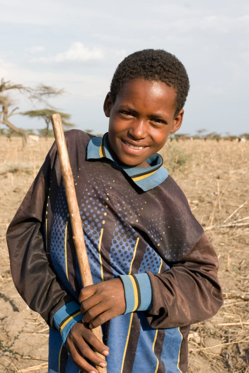 Disabled Boy in Ethiopia — Stock Image of boy with disability out in a field with a stick he uses to mind the family animals. — Ethiopia, Africa, African, Af...