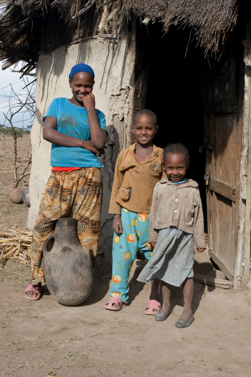 Children in Rural Africa — Poor children of Ethiopia stand outside the doorway to their mud hut, with water container — Ethiopia, Africa, African, Africans, ...