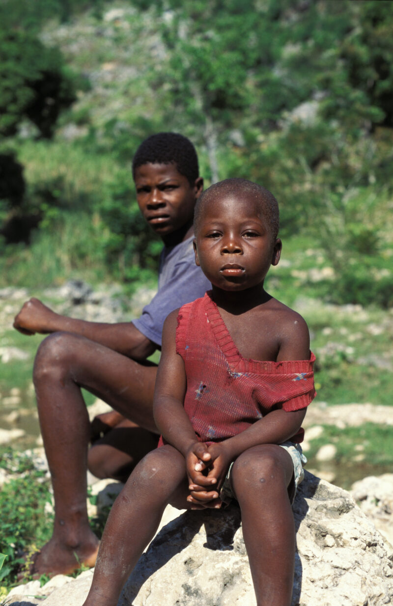 Stock Images of Haiti — Stock Image of Haiti: Boy sits on a rock by the road in Haiti — Haiti, Haitian, boy, boys, faces