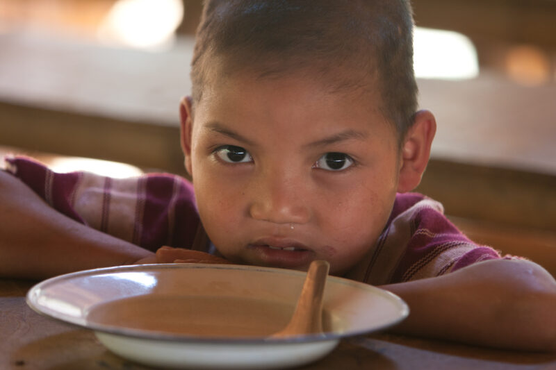 Getting a Hot Meal at School — Children eat a bowl of hot soup, as part of their school feeding program, at a Karen refugee camp, near the Thai border with M...