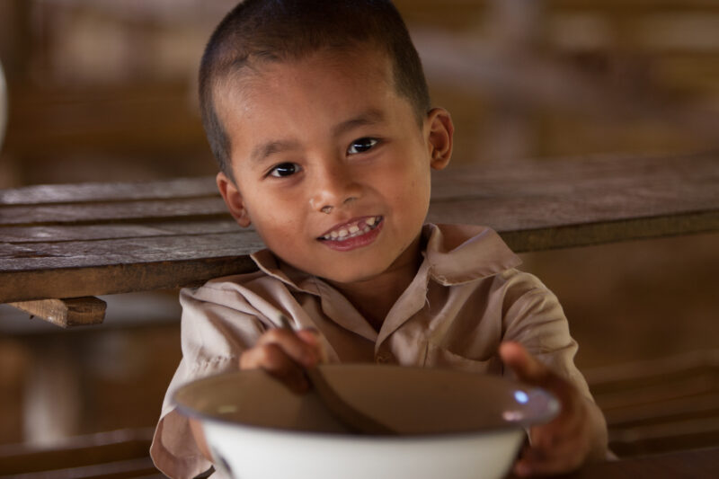 Getting a Hot Meal at School — Children eat a bowl of hot soup, as part of their school feeding program, at a Karen refugee camp, near the Thai border with M...