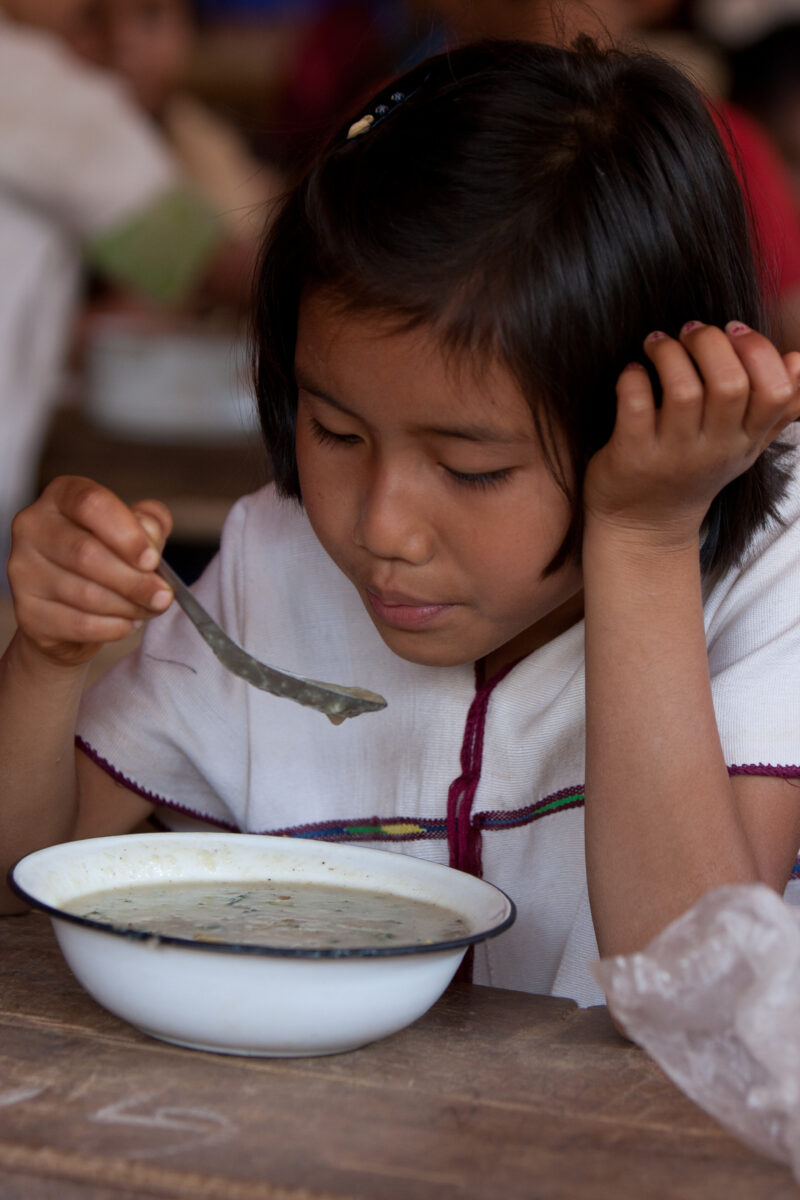 Getting a Hot Meal at School — Children eat a bowl of hot soup, as part of their school feeding program, at a Karen refugee camp, near the Thai border with M...