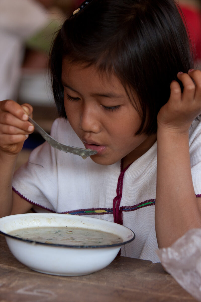 Getting a Hot Meal at School — Children eat a bowl of hot soup, as part of their school feeding program, at a Karen refugee camp, near the Thai border with M...